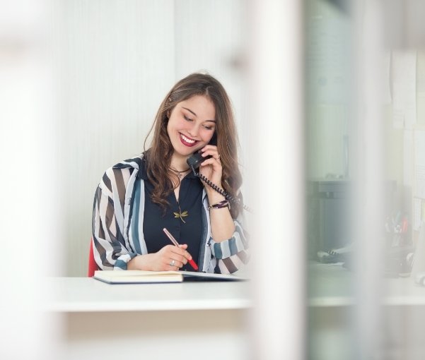 Smiling woman sitting at desk and talking on phone