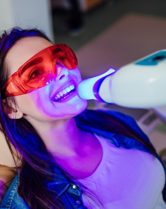 Woman getting professional teeth whitening in dental chair