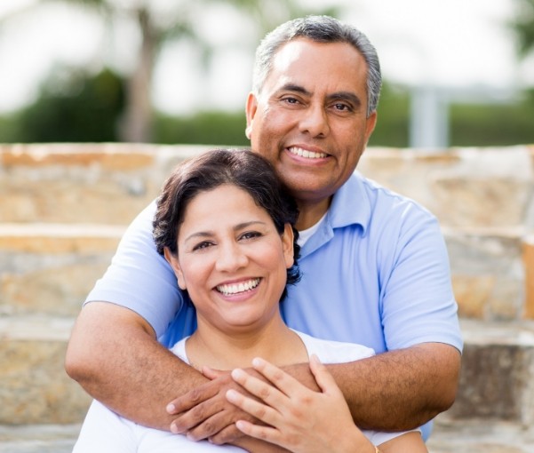 Man and woman hugging outdoors and smiling with dental implants in New York