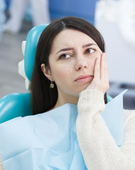 Woman holding her cheek in pain while visiting emergency dentist