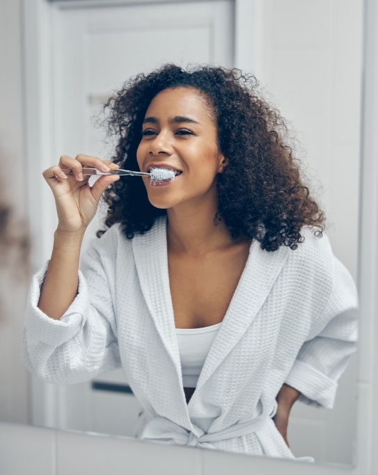 Woman smiling while brushing her teeth