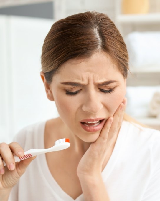 Woman in pain while holding a toothbrush with blood on it