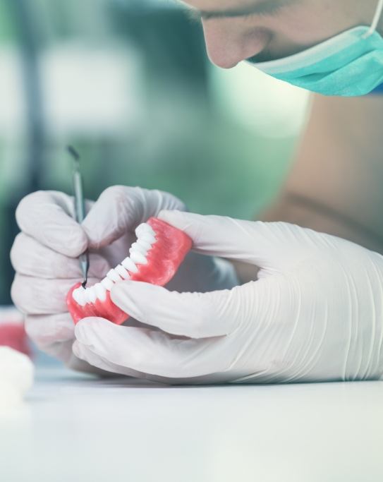 Dental professional adjusting a denture