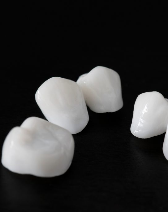 Five white dental crowns against black background