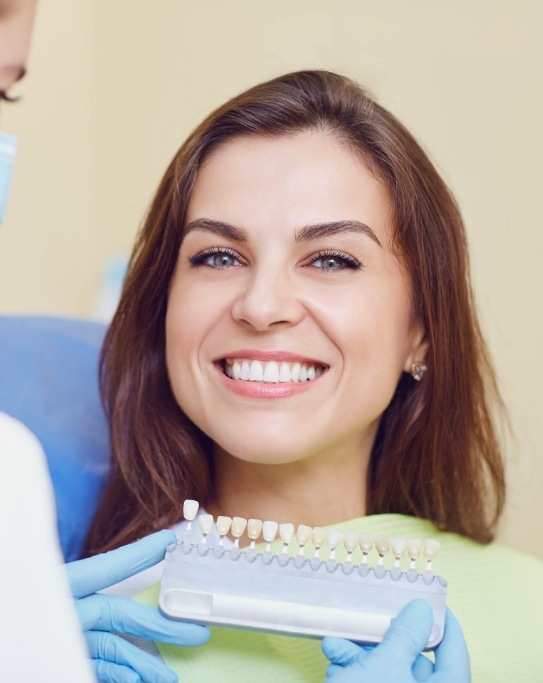 Dentist holding shade guide next to smiling patient