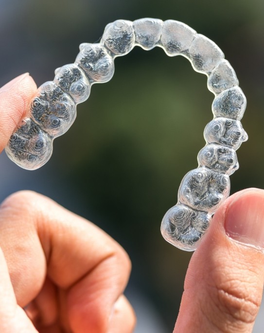 Hand holding an Invisalign clear aligner