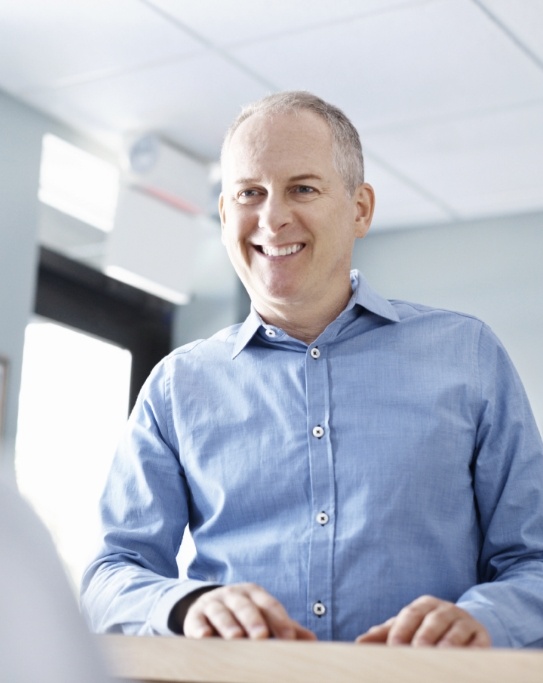 Man smiling at person behind front desk