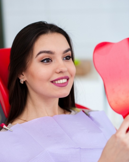 Dental patient admiring her smile in a mirror