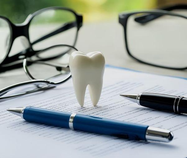 Two pens and eyeglasses with insurance document