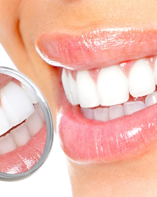 Close up of dental mirror reflecting smile with white teeth