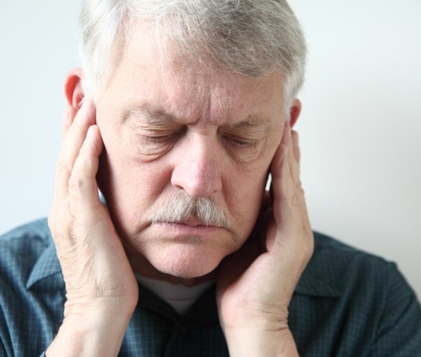 Man holding his temples in pain before T M J treatment in New York