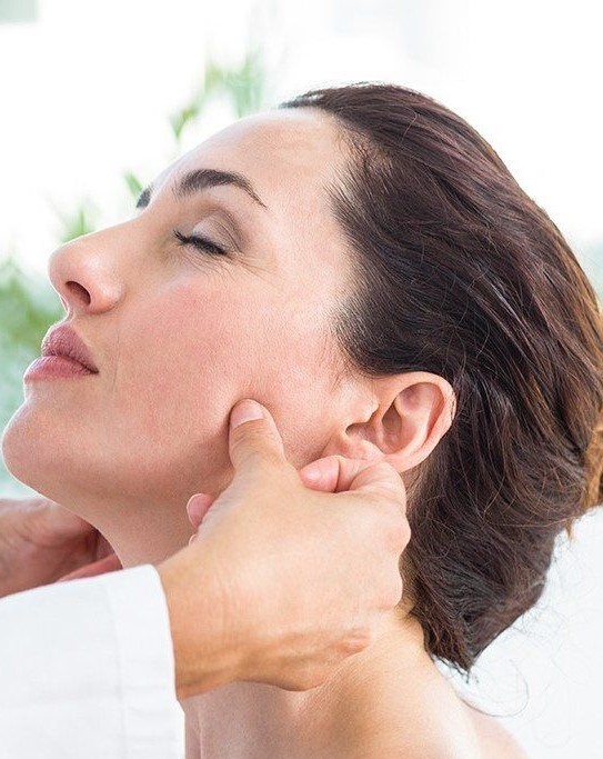 Woman having her jaw joints adjusted by a dentist