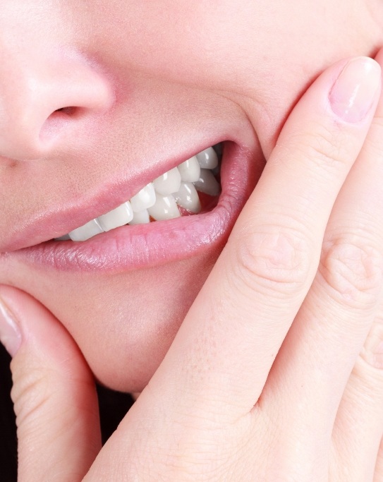 Close up of person wincing and holding their cheek in pain