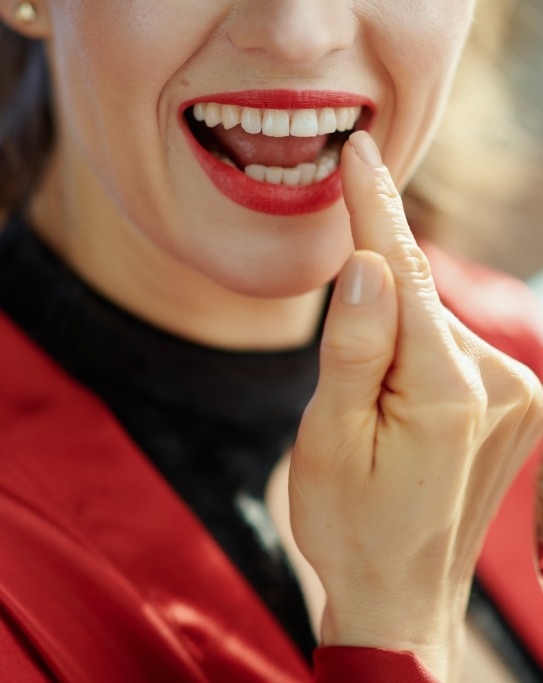 Woman with red lipstick looking at her teeth in a mirror