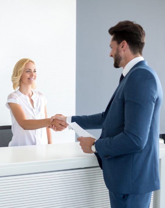 Man in suit shaking hands with dental office receptionist