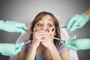 Woman in the dental chair covering her mouth