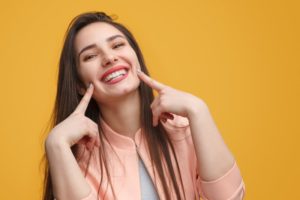 Woman pointing to her smile.