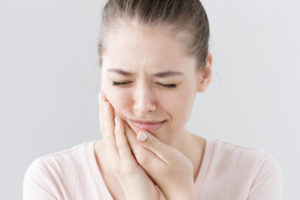 A woman touches her mouth in pain