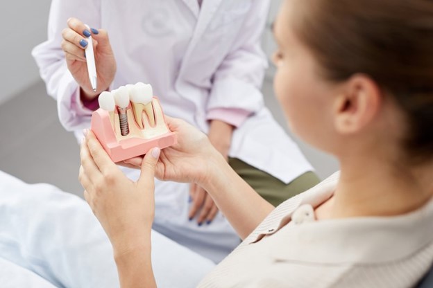 Patient and dentist examining a model of dental implants.