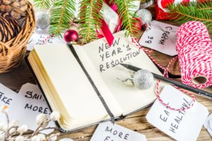 Notebook with New Year's Resolutions on a table with holiday decor