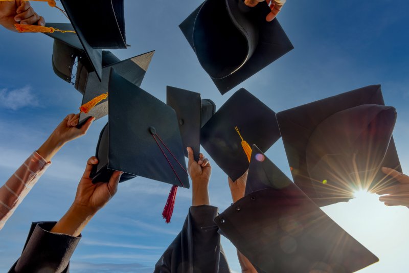 Arms holding and throwing graduation caps